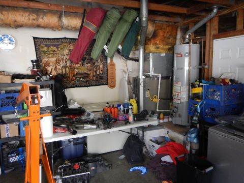 2003 Ford Crown Victoria - cluttered garage corner with a workbench of tools and parts, a hanging tapestry, water heater and an orange engine stand.