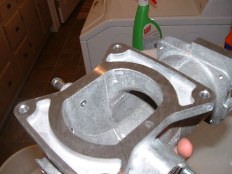 1998 Ford Crown Victoria - An aluminum intake manifold part is shown, with laundry appliances and a cleaning spray bottle visible in the background.