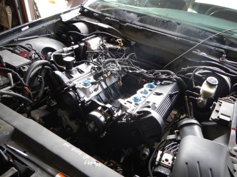 2003 Ford Crown Victoria - Top view of a V8 engine freshly set in an engine bay, intake manifold centered with a handwritten mileage note below.