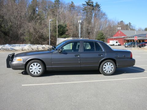 2001 Ford Crown Victoria - A dark grey 2001 Ford Crown Victoria is parked in a lot on a sunny day.