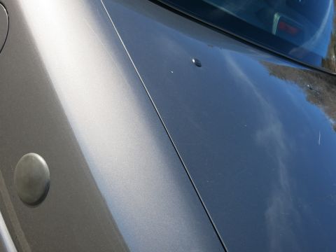 2001 Ford Crown Victoria - Close-up of a gray car's hood, showing a seam and a circular cap.