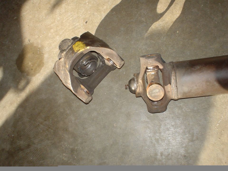 Close-up of a broken driveshaft universal joint on a concrete surface