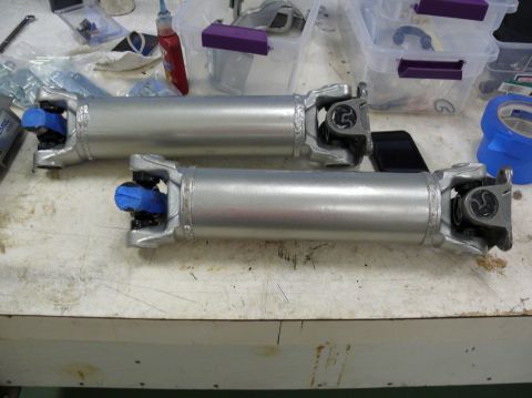 Two driveshafts on a workbench with blue protective caps