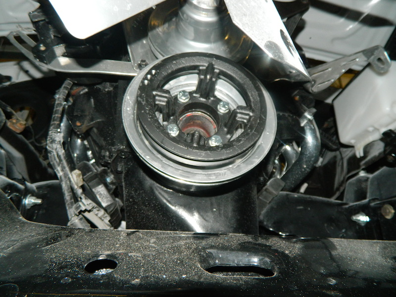Close-up of an engine pulley with a fan visible above it