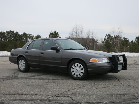 2001 Ford Crown Victoria - A dark grey 2001 Ford Crown Victoria is shown from a three-quarter front angle, equipped with a push bar.