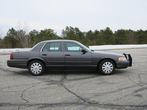 2001 Ford Crown Victoria - Side view of a 2001 Ford Crown Victoria sedan parked on cracked asphalt.