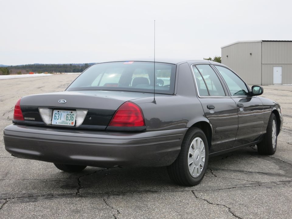 Rear 3/4 view of a dark grey Ford Crown Victoria with a license plate reading 631 636