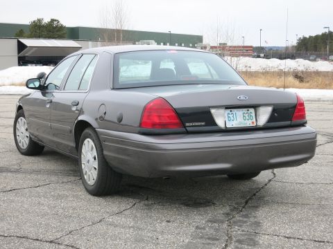 2001 Ford Crown Victoria - Rear view of a grey 2001 Ford Crown Victoria parked on cracked asphalt.