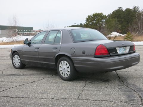 2001 Ford Crown Victoria - This Ford Crown Victoria is seen from the rear-three-quarter view, parked outdoors on a cloudy day.