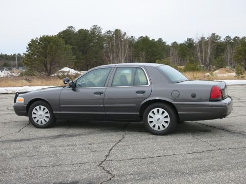 2001 Ford Crown Victoria - A grey 2001 Ford Crown Victoria is shown from the side, parked outdoors with trees in the background.