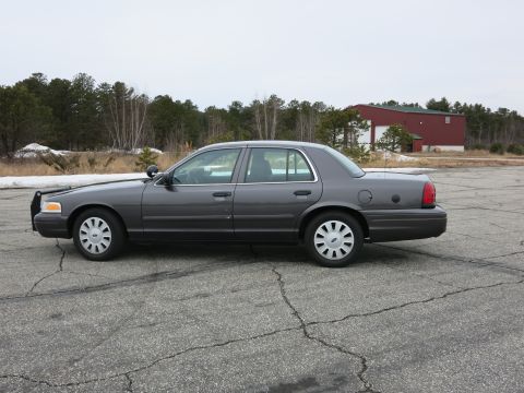 2001 Ford Crown Victoria - Side profile of a grey 2001 Ford Crown Victoria sedan parked on asphalt.