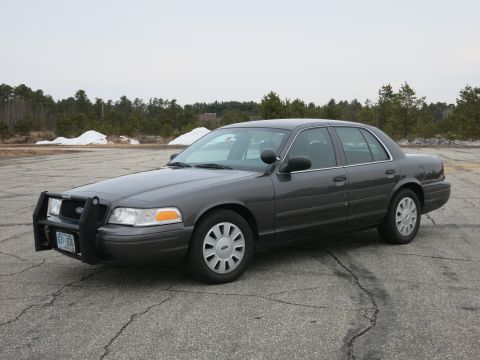 2001 Ford Crown Victoria - Dark grey 2001 Ford Crown Victoria police car with a push bumper is parked outside.