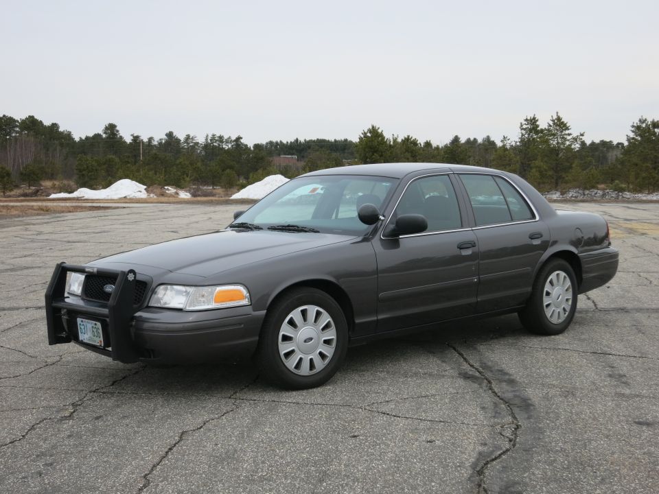 2001 Ford Crown Victoria police car with push bumper, parked on cracked asphalt