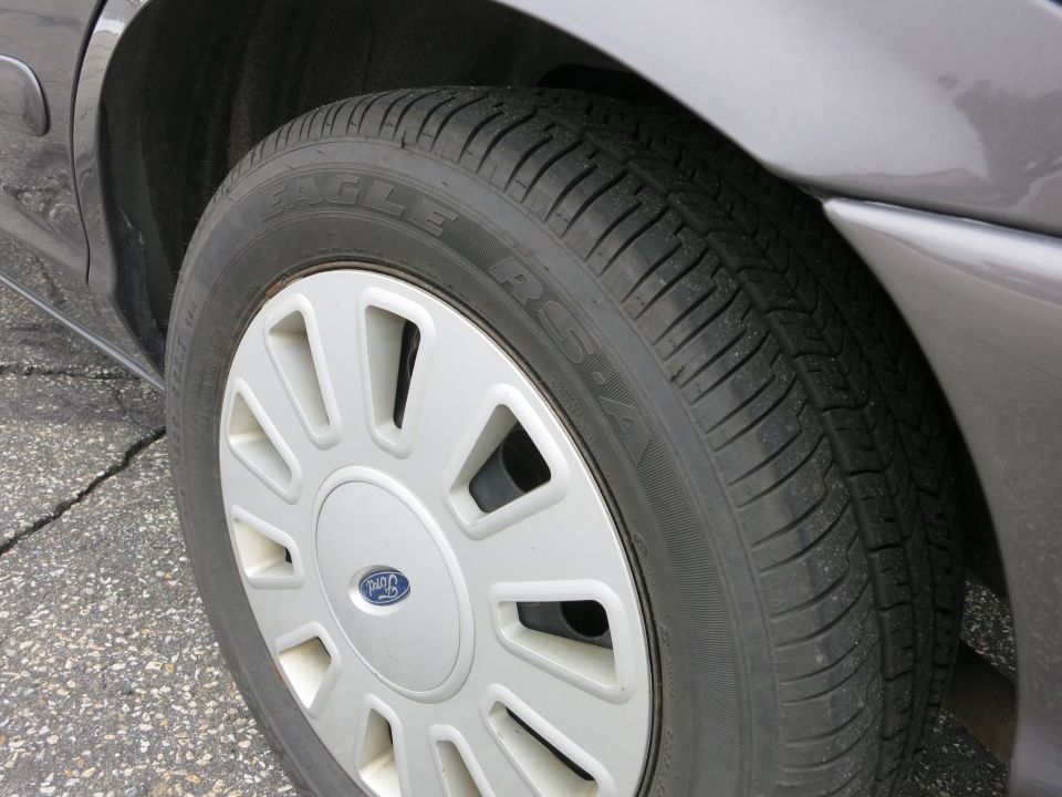 Close-up of a 2001 Ford Crown Victoria's front passenger-side wheel and tire. The tire is a Goodyear Eagle RS-A