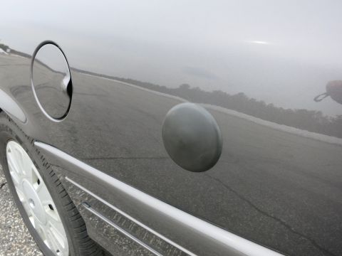 2001 Ford Crown Victoria - Close-up of a car's fuel door and gas cap on the side panel.