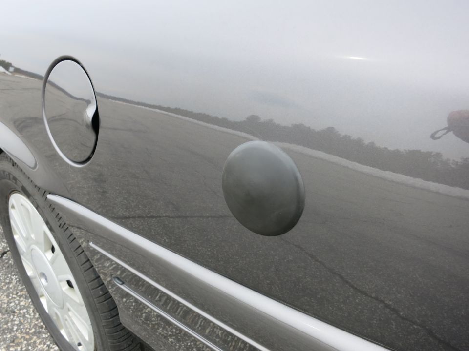 Gray car's fuel door and gas cap on the side panel