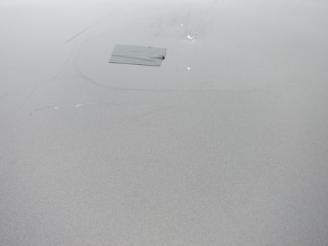 2001 Ford Crown Victoria - Close-up of a silver car hood showing a piece of duct tape and minor imperfections.