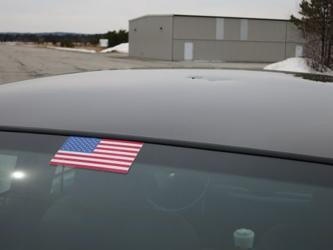 2001 Ford Crown Victoria - American flag sticker adhered to the rear window of a dark-colored vehicle.