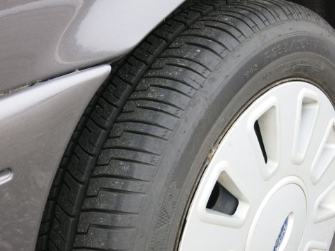 2001 Ford Crown Victoria - Close-up of a tire and wheel assembly, showing tire size P235/55R16 and a Ford logo on the hubcap.