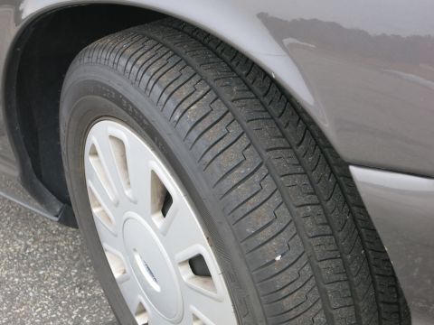 2001 Ford Crown Victoria - The front passenger side tire and fender of a 2001 Ford Crown Victoria are shown in this close-up shot.