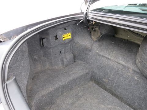 2001 Ford Crown Victoria - The trunk interior is lined with gray carpet and features a yellow warning sticker on the left side panel.
