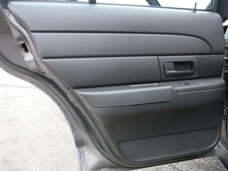 Gray interior door panel of a 2001 Ford Crown Victoria. View shows door handle and armrest