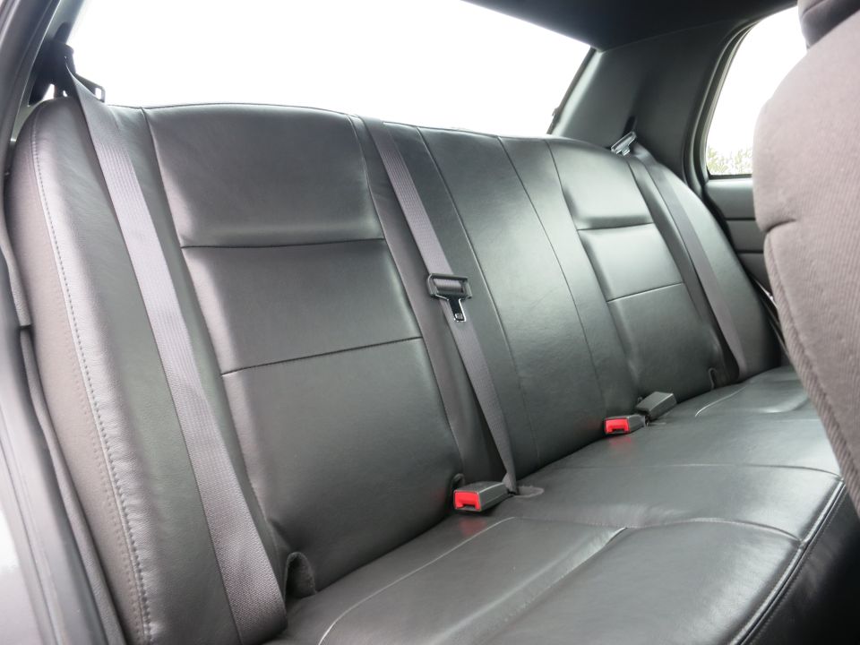 Black leather rear seat with gray seatbelts and red buckle receivers