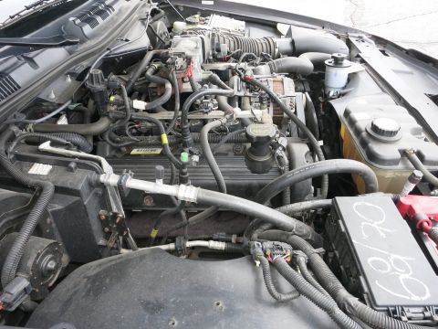 2001 Ford Crown Victoria - The engine bay of a 2001 Ford Crown Victoria is visible, with various mechanical parts and wiring harnesses.