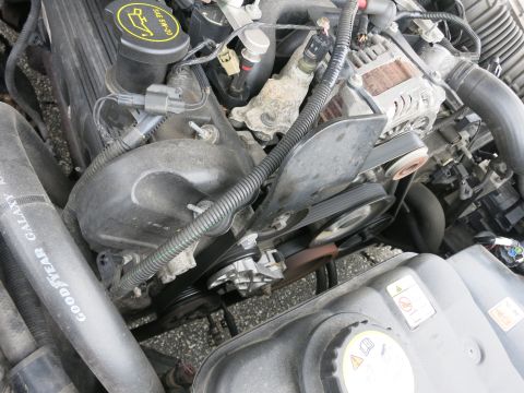 2001 Ford Crown Victoria - Close-up of an engine bay, showing serpentine belts, pulleys, and a portion of a Goodyear tire.