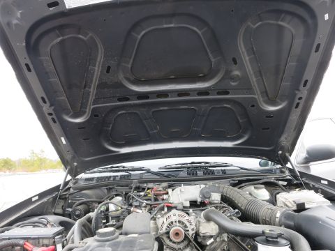 2001 Ford Crown Victoria - The engine compartment of a 2001 Ford Crown Victoria is visible with the hood raised, revealing the engine and surrounding parts.