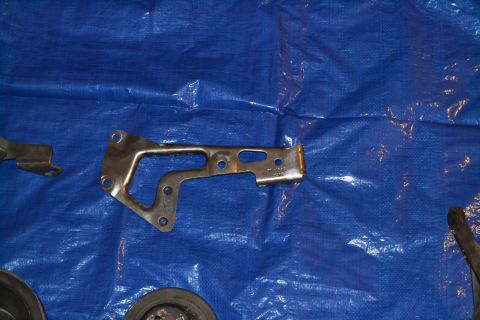 1981 Ford F-250 - A metal bracket and a pulley are shown on a blue tarp background.