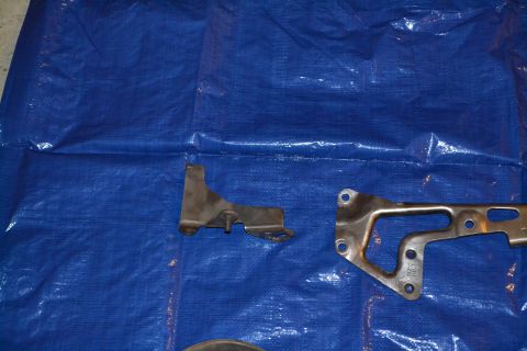 1981 Ford F-250 - Two metal brackets are laid out on a blue tarp, possibly for repair or replacement.