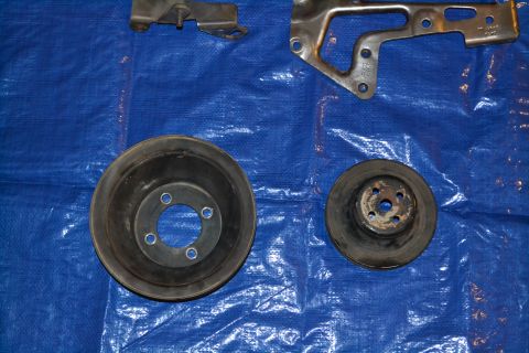 1981 Ford F-250 - Vehicle parts, including pulleys and a bracket, are laid out on a blue tarp.
