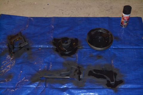 1981 Ford F-250 - Several automotive parts are laid out on a blue tarp, along with a can of black spray paint, suggesting a painting or restoration project.