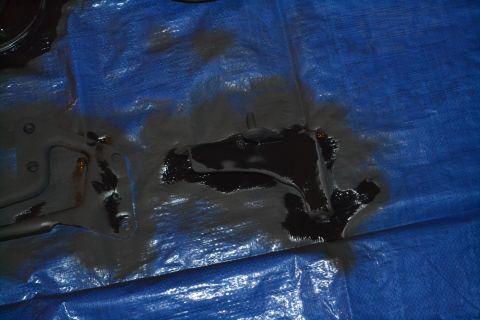 1981 Ford F-250 - A dark fluid has leaked onto a blue tarp, obscuring the underlying surface and parts.