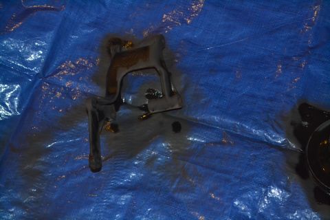 1981 Ford F-250 - A dark metal component, possibly from an engine, lies on a blue tarp stained with oil.