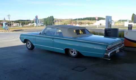 1964 Mercury Monterey - A turquoise 1964 Mercury Monterey convertible is parked at a gas station under a clear sky.