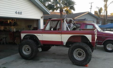 1968 Ford Bronco - A modified red and white Ford Bronco sits in a driveway next to another vehicle.