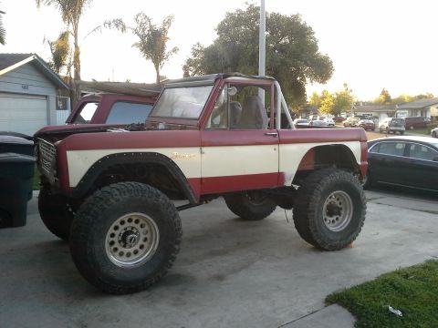 1968 Ford Bronco - This lifted Ford Bronco is parked in a residential area, with other cars visible in the background.