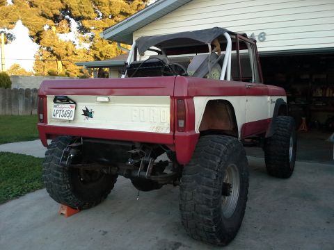 1968 Ford Bronco - This 1968 Ford Bronco features a two-tone red and white paint job and is equipped with oversized off-road tires.