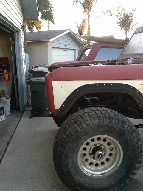 1968 Ford Bronco - Close-up of a 1968 Ford Bronco fender and large off-road tire, with a second Bronco in the background.