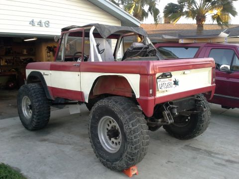 1968 Ford Bronco - A modified 1968 Ford Bronco with a two-tone paint job and oversized tires is parked in a driveway.