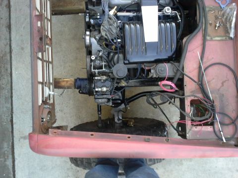 1968 Ford Bronco - The engine bay of a red vehicle is shown, with the engine and various wires exposed.