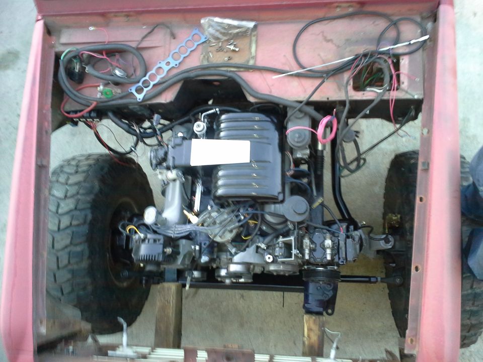 Vehicle engine and front suspension assembly, with red body panels visible