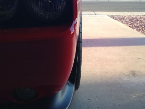 2010 Dodge Challenger - The front corner of a red car is shown, with a portion of the headlight and fender visible.