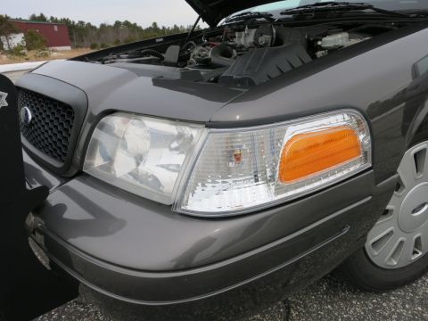 2001 Ford Crown Victoria - The front end of a grey Ford Crown Victoria is shown with the hood open, revealing the engine compartment.