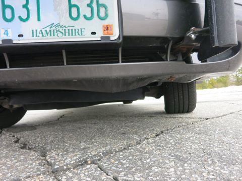 2001 Ford Crown Victoria - A low-angle view of the rear bumper and tire of a dark gray vehicle, with a New Hampshire license plate visible.
