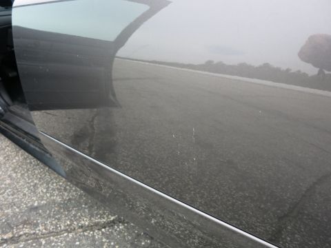 2001 Ford Crown Victoria - Close-up of a gray car door showing minor scratches and reflections of the surrounding environment.