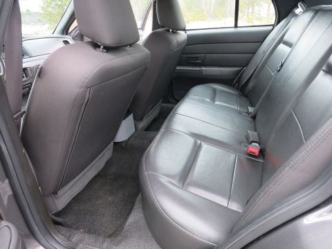 2001 Ford Crown Victoria - The interior of a car shows the back seat and door panel, with a focus on the black leather seats and seatbelt.