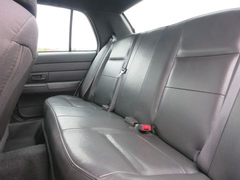 2001 Ford Crown Victoria - Rear interior view of a vehicle, showing the black leatherette seats and seatbelts.